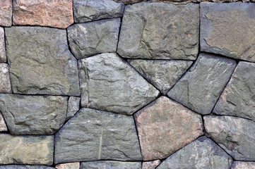 Old weathered wall made of granite stones, abstract background.