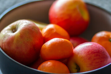 Bowl of fresh organic oranges and apples on a table