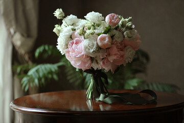 Bridal bouquet of white roses and peonies flowers with green festive ribbon in the morning before the wedding ceremony