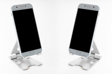 Close up of a device to support the mobile phone. Copy space available for advertising. Two cell phones placed opposite each other with a completely black screen.