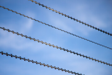 close up of three spikes of a barbered wire, blue sky as background