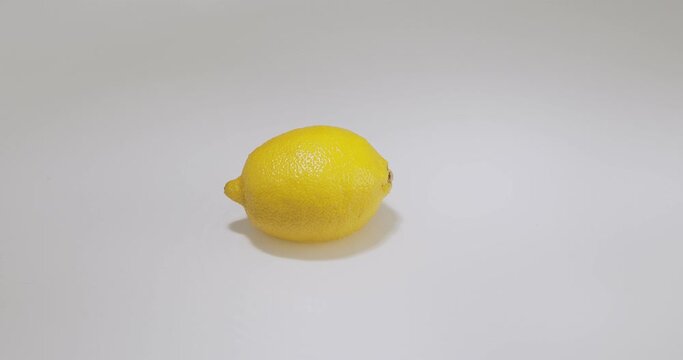 Hand rotate lemon lying in water, natural fruit citron on studio backdrop with copyspace. Vitamins, healthy eating store