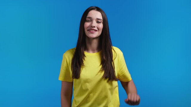 Friendly woman waving hand - hello, or goodbye, chao, adios. Parting, say bye to camera. Beautiful girl waving hand on blue studio background