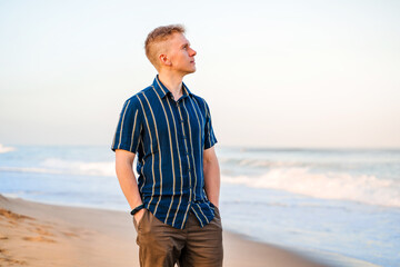 A young blonde man walks on the sand at Manhattan Beach in the early morning, Los Angeles