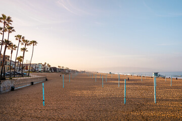 Fototapeta na wymiar Early morning sunrise and soft haze on Manhattan Beach, waves and rescue towers, Los Angeles