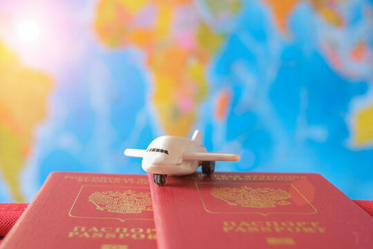 small plane stands on passports against the background of the world map. The concept is freedom of travel, accessibility, anticipation of adventure, discovery of new places Horizontal photo, close-up