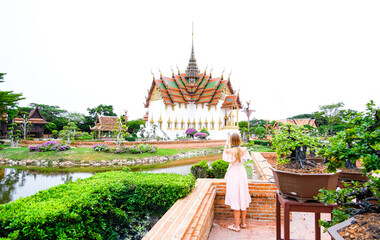 A girl in a pink dress in front of the Dusit Maha Prasat Throne Hall at Wat Phra Kaew. Bangkok, Thailand. 