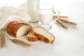 Sliced bread, ears of wheat, milk on a white wooden table. Symbols of Jewish holiday - Shavuot.
