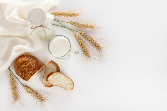 Dairy products and bread over white wooden background. Symbols of Jewish holiday - Shavuot. Top view