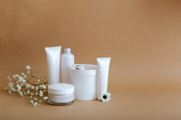 Set natural beauty cosmetic skincare products with flowers sea shells on beige background with copy space. White kit cream jar tube cosmetic products for body treatment skin care cosmetic mockup