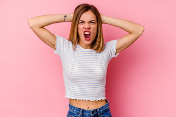 Young caucasian woman isolated on pink background screaming with rage.