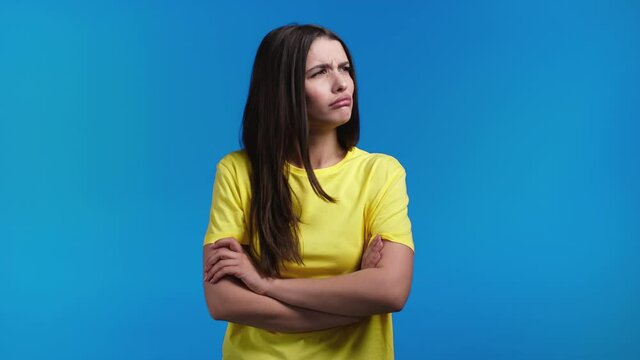 Offended woman keeping arms crossed, feeling mad at someone on blue studio background. Human facial expressions, emotions and feelings. Body language. 