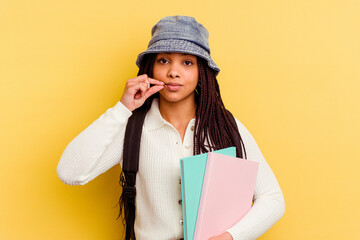 Young african american student woman isolated on yellow background with fingers on lips keeping a secret.