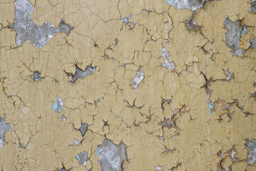 Peeling paint on the wall. Old concrete wall with cracked flaking paint. Weathered rough painted surface with patterns of cracks and peeling. Grunge texture for background and design. High resolution.