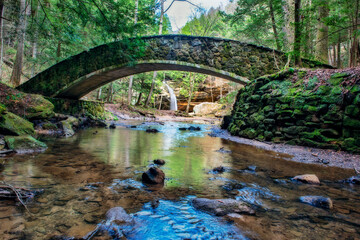 Fototapeta na wymiar Waterfall seen through the arch of a stone bridge.