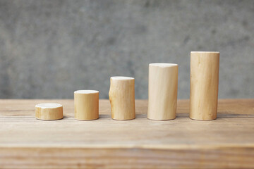 Thin and short barkless wooden log blocks on wooden table. Barkless cedar log set lined up individually in order of height on wooden background. 