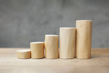 Thin and short barkless wooden log blocks on wooden table. Barkless cedar log set lined up closely together in order of height on wooden background. 