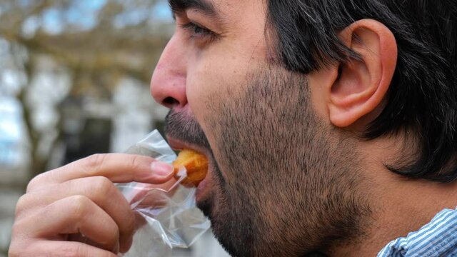 Side view of man eating Madeleine cake