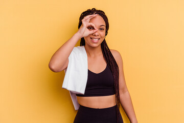 Young sport african american woman holding a towel isolated on yellow background excited keeping ok gesture on eye.