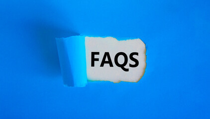 FAQS, frequently asked questions symbol. Concept words 'FAQS, frequently asked questions' appearing behind torn blue paper. Beautiful blue background, copy space. Business and FAQS concept.