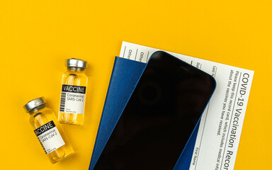 New normal safe travel in summer, vaccine vials and covid-19 vaccination record card, top view photo
