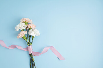 Bouquet of pink carnation flowers over blue background. Saint valentine, mothers day idea