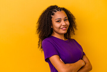 Young african american woman isolated on yellow background smiling confident with crossed arms.