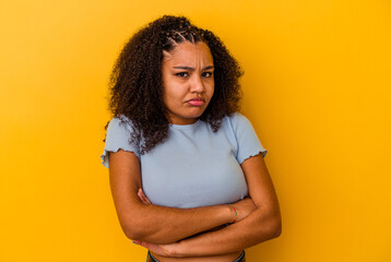Young african american woman isolated on yellow background blows cheeks, has tired expression....