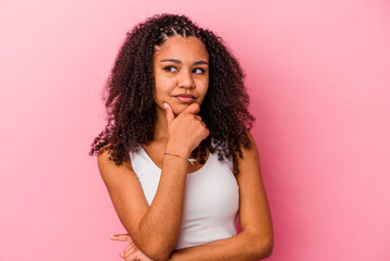 Young african american woman isolated on pink background thinking and looking up, being reflective, contemplating, having a fantasy.