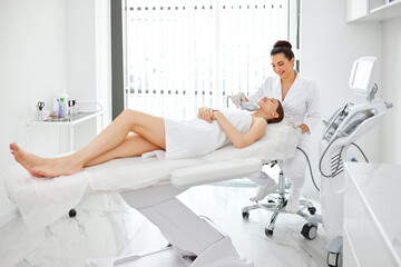 Cosmetologist using laser machine for facial treatment of client and SMAS lifting