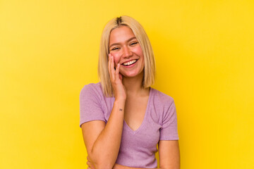 Young venezuelan woman isolated on yellow background laughs happily and has fun keeping hands on...