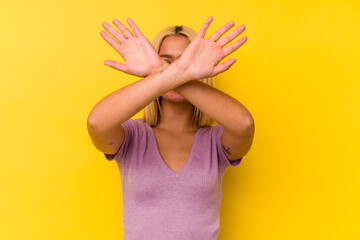 Young venezuelan woman isolated on yellow background keeping two arms crossed, denial concept.
