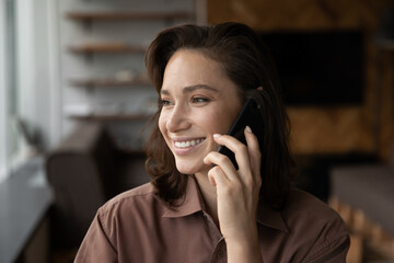 Crop close up of smiling young Caucasian woman hold smartphone talk speak with client or customer....