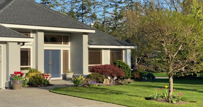 Establishing shot of two story stucco luxury house with garage door, big tree and nice landscape in Vancouver, Canada, North America. Day time on April 2021.
