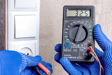 handyman electrician measuring wall outlet voltage at living room. outlet repair concept. test house wiring conceptual