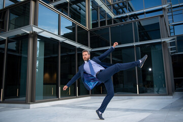 Fototapeta na wymiar Business excitement. Business man keeping arms raised and expressing positivity outdoors. Businessman jumping for joy celebrating a successful.