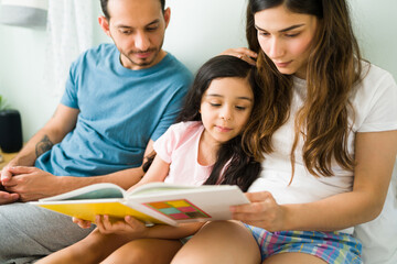 Elementary kid learning how to read with her parents