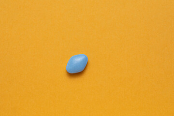 Blue pill on orange background. Erectile Dysfunction Pill.
Mans health and sexual problems. Male power and libido