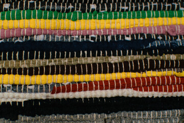 Woven surface from interwoven rags and thread of different colors, carpet fragment