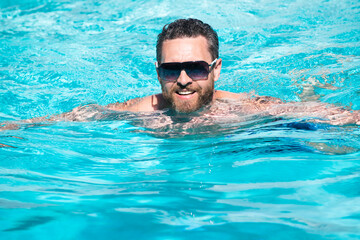 Pool resort. Handsome man at summer vacation. Man in sunglasses relaxing in swimming pool.