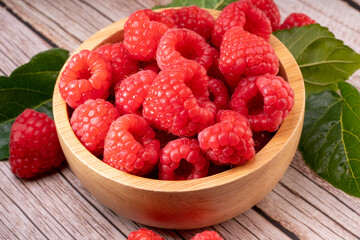 Raspberry fruit on wooden bowl in Wooden background, Raspberries with leaves on Wooden background.