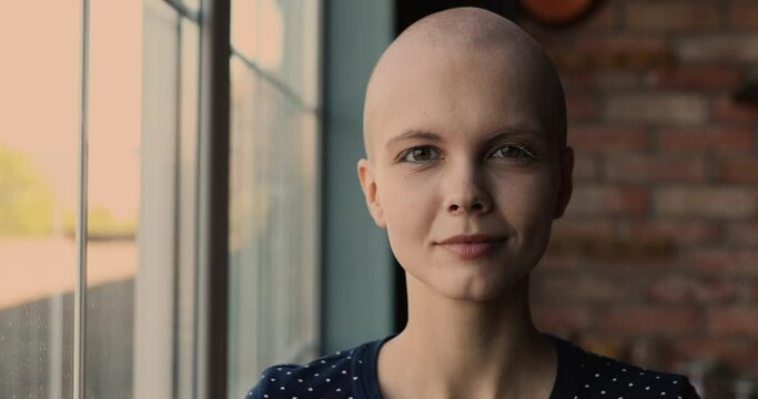 Head shot sincere happy young woman with hairless head looking at camera, feeling joyful of overcoming cancer disease. Portrait of smiling female patients with oncology remission, hope for recovery.