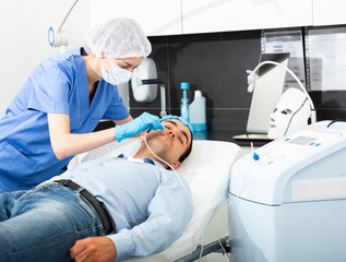 Portrait of male patient during cosmetology procedure in beauty clinic, getting carbon dioxide...