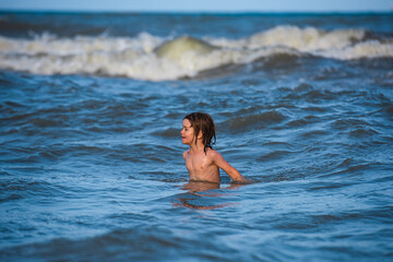 Kid swimming having fun and jumping in the waves of the sea. Sea vacation for family.