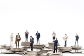 Business amd Money Concept. Group of businessman miniature figures people standing on stack of silver coin on white background.