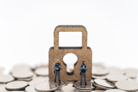 Money and Security Concept. Two soldier /police guard miniature figures people standing on pile of coins with wooden master key lock icon on white background.