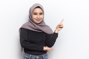 Smiling and pointing copyspace of Young beautiful muslim asian women dress Veil(Hijab) and black shirt isolated on white background