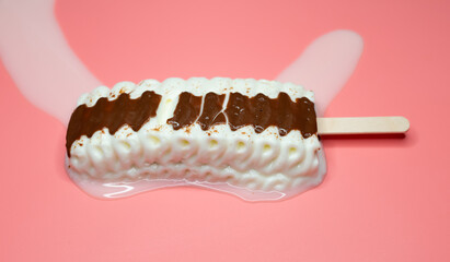 angle view vanilla and chocolate flavor popsicle melting on a pink background