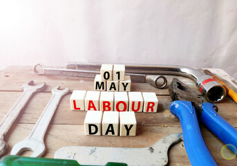 first May is celebrated as Labourers day , poster of may day celebration with tools on Wooden background.