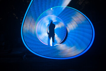 One person standing alone against a Colourful circle light painting as the backdrop	
